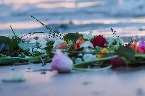Gezamenlijke bloemenlegging bij de uitvaart op het strand, symbool voor afscheid en herinnering.