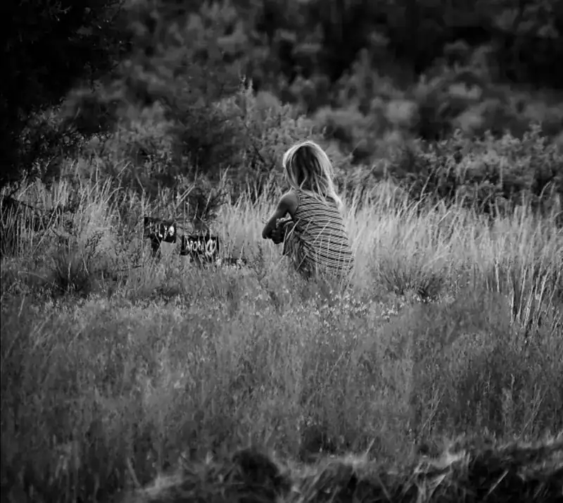 Herinnering aan overleden geliefde, jonge vrouw zit in een veld met bloemen, rust en bezinning, uitvaartverzorging De Dageraad.